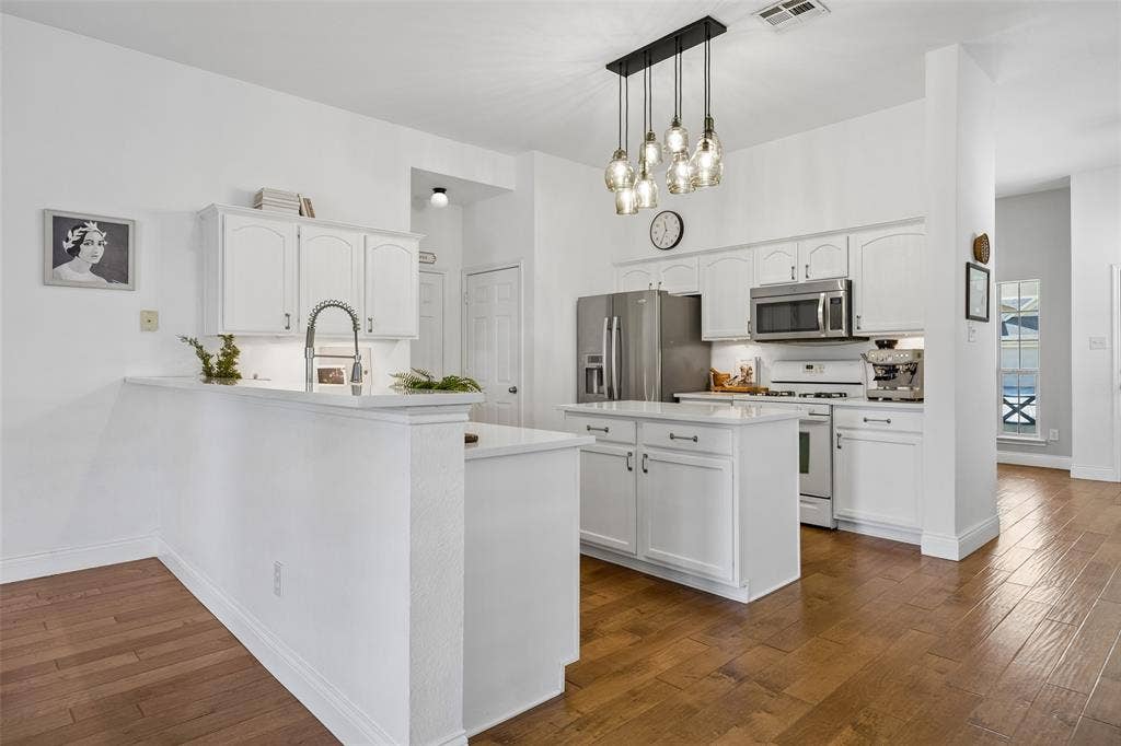 9828 Meadow Rue Drive, McKinney, TX 75072 Beautifully updated kitchen with white cabinetry, quartz countertops and a spacious island.