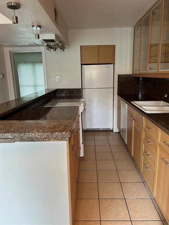 4112 Bowser Avenue, #210, Dallas, TX 75219 Kitchen with tile flooring, granite countertops, wood-finish cabinetry, and glass-front upper cabinets