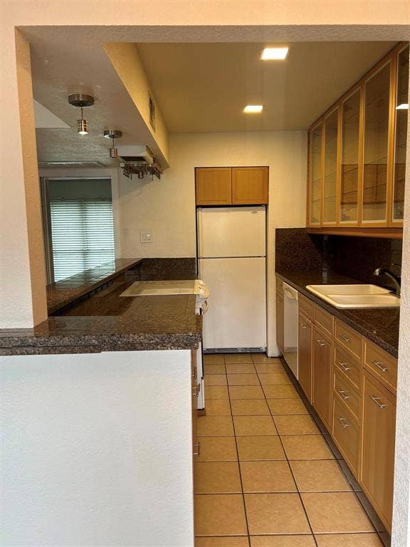4112 Bowser Avenue, #210, Dallas, TX 75219 Kitchen featuring tile flooring, wood cabinetry with glass-front uppers, solid surface countertops, and recessed lighting
