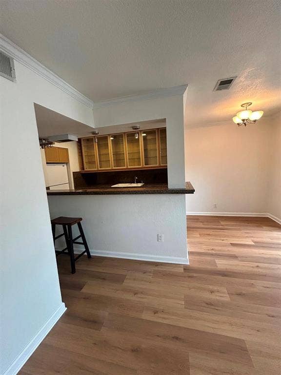 4112 Bowser Avenue, #210, Dallas, TX 75219 Wood-finish flooring throughout, crown molding, built-in upper cabinetry with glass fronts, recessed lighting, and a multi-bulb ceiling fixture