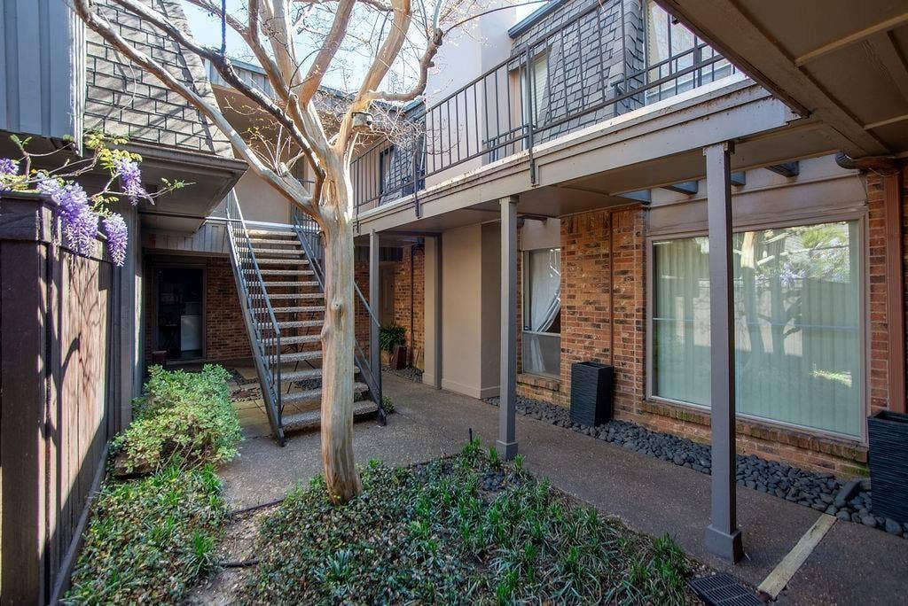4112 Bowser Avenue, #210, Dallas, TX 75219 Courtyard entry featuring a mature tree, metal staircase, brick exterior, and covered walkway