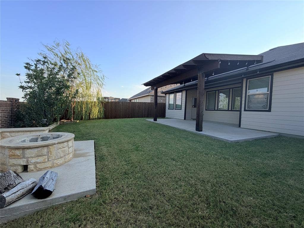 3308 Chasemoor Drive, Denton, TX 76207 Expansive backyard featuring a stone-clad fire pit, extended concrete patio, and a covered pergola
