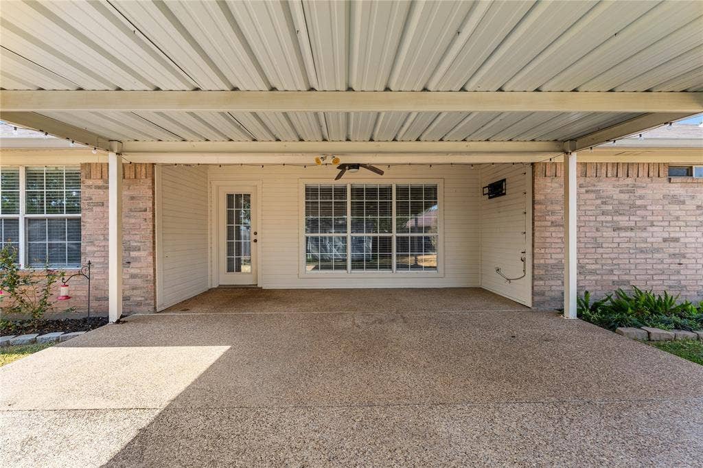 624 Willow Creek Drive, Hewitt, TX 76643 Expansive covered patio with exposed aggregate concrete flooring, featuring a ceiling fan and exterior lighting, alongside a brick and siding exterior
