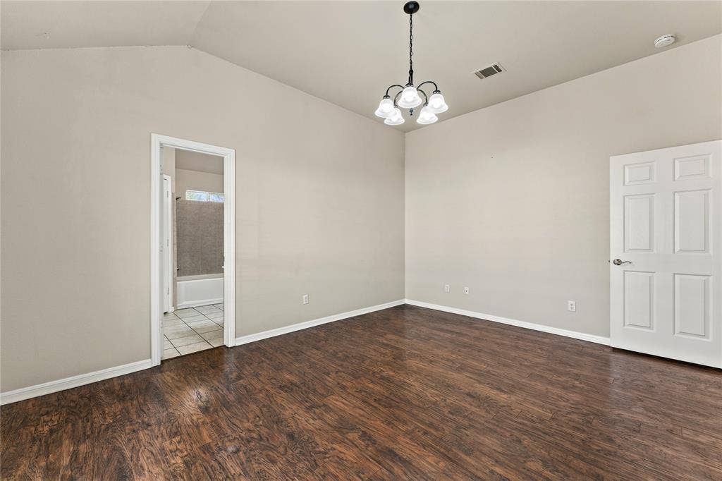 624 Willow Creek Drive, Hewitt, TX 76643 Vaulted ceiling with an attached chandelier, wood-finish flooring, and a six-panel interior door
