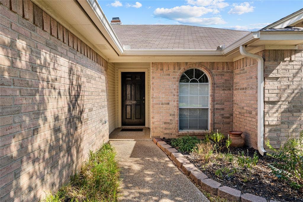624 Willow Creek Drive, Hewitt, TX 76643 Brick exterior with an arched window, dark paneled entry door, concrete walkway, and landscaped garden bed with edging