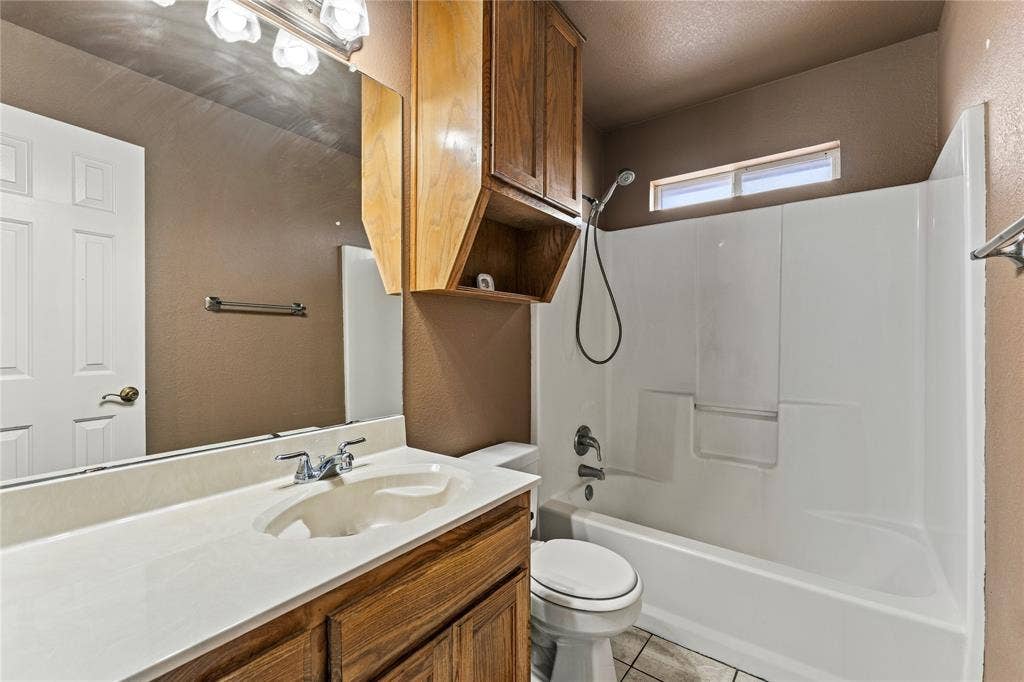 624 Willow Creek Drive, Hewitt, TX 76643 Vanity with integrated sink, wood-finish cabinetry, full-width mirror, shower/tub combination, and an upper window