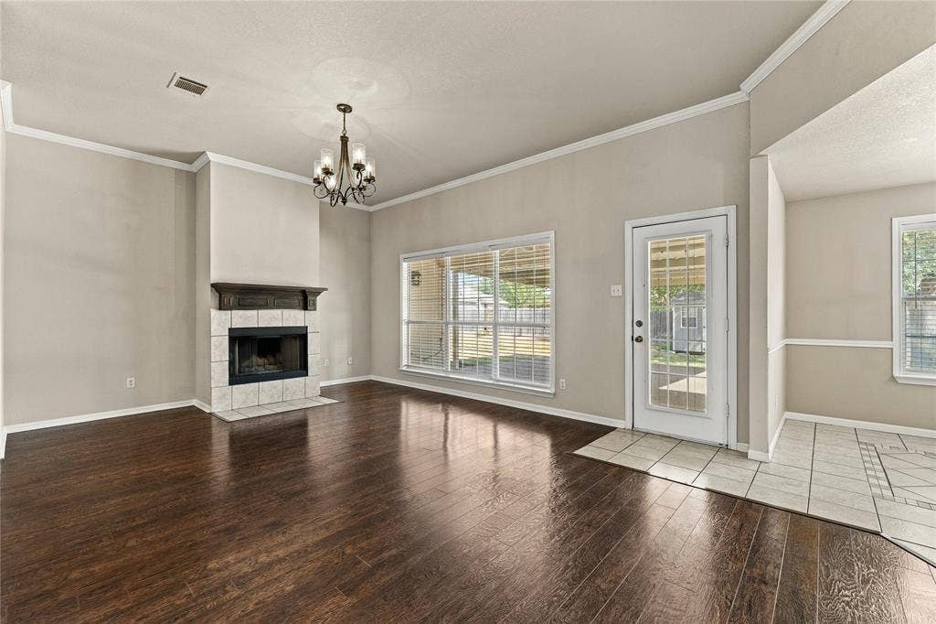 624 Willow Creek Drive, Hewitt, TX 76643 Wood-finish flooring, tiled fireplace with mantel, ceiling-mounted chandelier, glass-paneled exterior door, and multiple windows