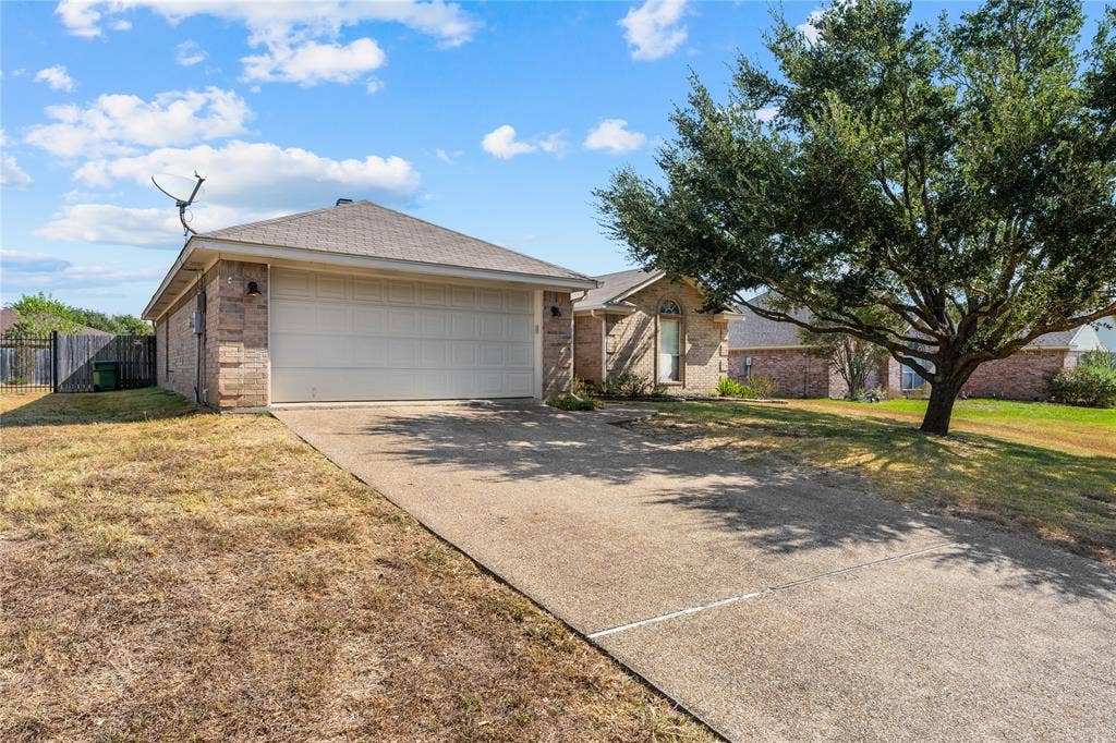 624 Willow Creek Drive, Hewitt, TX 76643 Brick exterior with an attached garage, paved driveway, and mature trees