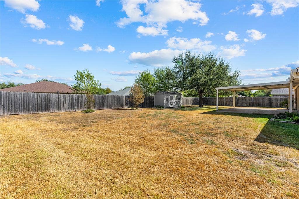 624 Willow Creek Drive, Hewitt, TX 76643 Expansive outdoor space featuring a covered patio, a detached storage shed, mature trees, and a perimeter wood fence