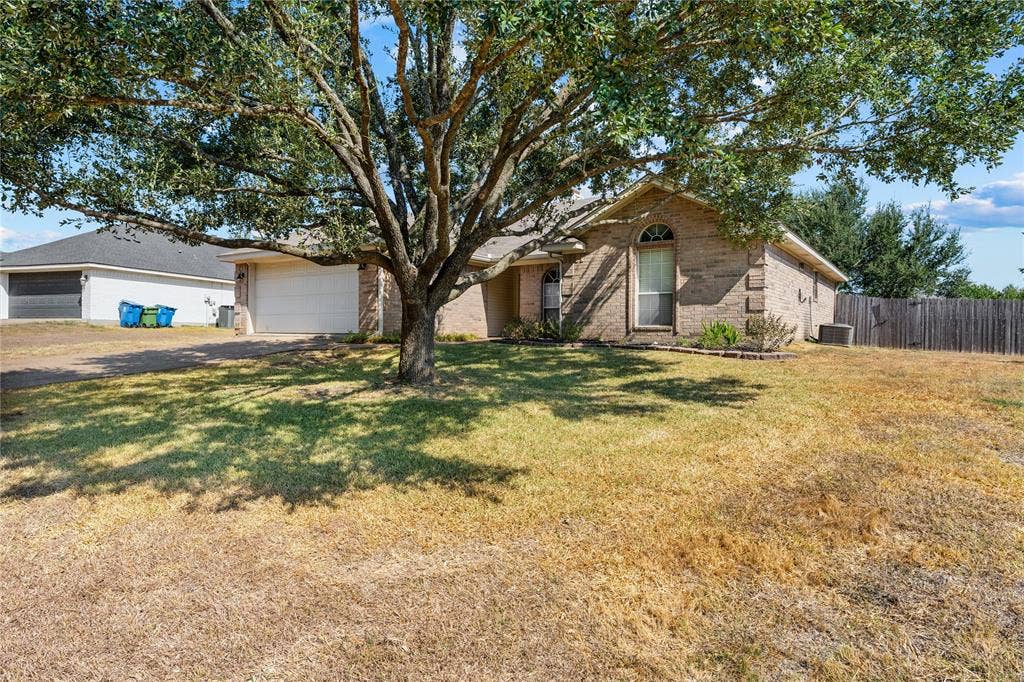 624 Willow Creek Drive, Hewitt, TX 76643 Brick facade residence featuring an arched window, a two-car garage, and a large mature tree
