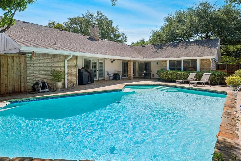 7603 Queens Ferry Lane, Dallas, TX 75248 Expansive outdoor patio with a built-in swimming pool, integrated steps, and a stone-capped pool edge