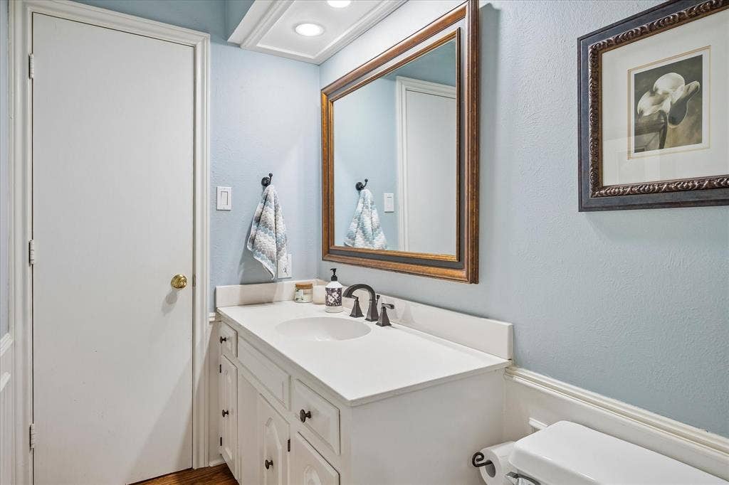 7603 Queens Ferry Lane, Dallas, TX 75248 White vanity with under-sink storage, integrated basin, and dark bronze-finish fixtures
