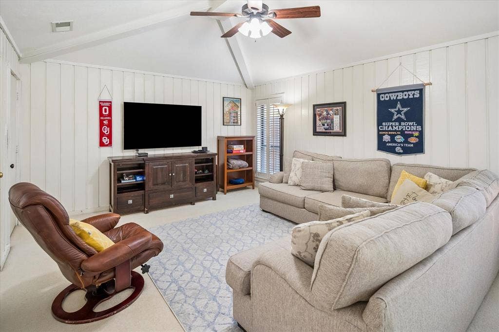 7603 Queens Ferry Lane, Dallas, TX 75248 Vaulted ceiling with exposed beams, wood-tone ceiling fan, and painted vertical paneling