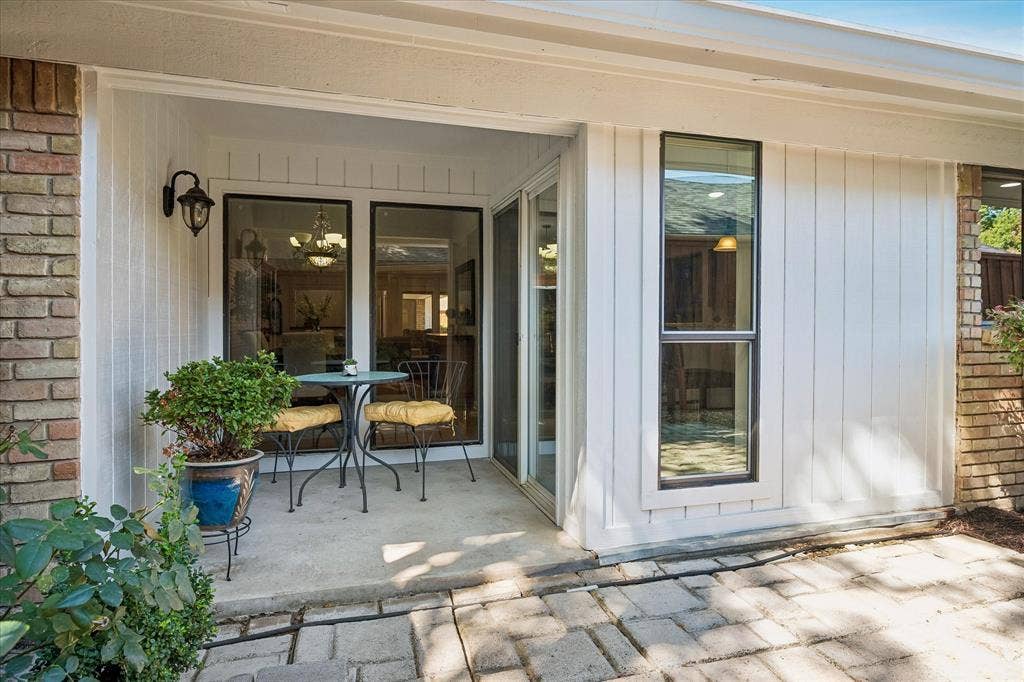 7603 Queens Ferry Lane, Dallas, TX 75248 Covered patio with brick and vertical panel siding, featuring a concrete pad and paver walkway