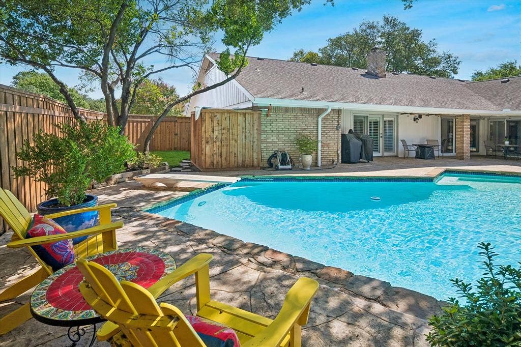 7603 Queens Ferry Lane, Dallas, TX 75248 Swimming pool with stone coping, a paved deck, wood privacy fence and green space
