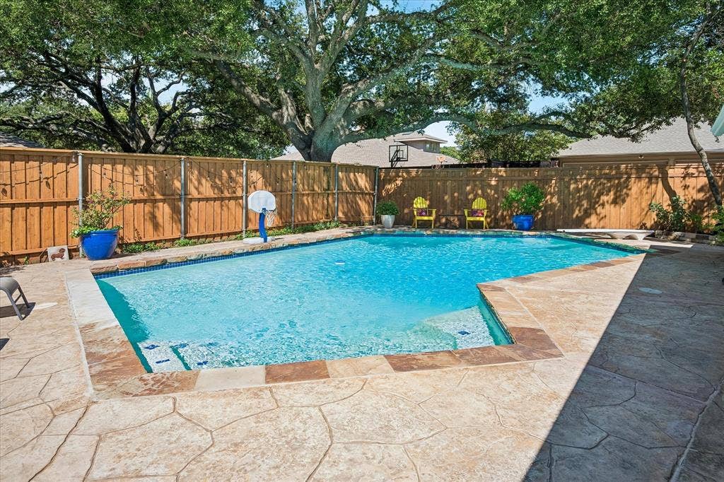 7603 Queens Ferry Lane, Dallas, TX 75248 Swimming pool with integrated steps, surrounded by stamped concrete decking and a wood privacy fence