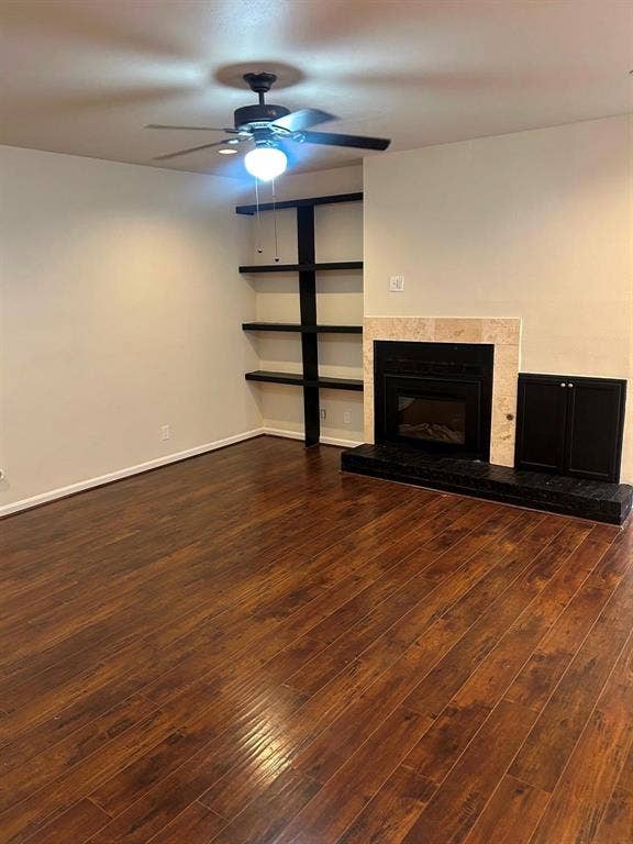 7525 Holly Hill Drive, #45, Dallas, TX 75231 Wood-finish flooring, built-in shelving, ceiling fan with integrated lighting, and a fireplace with a stone surround and hearth
