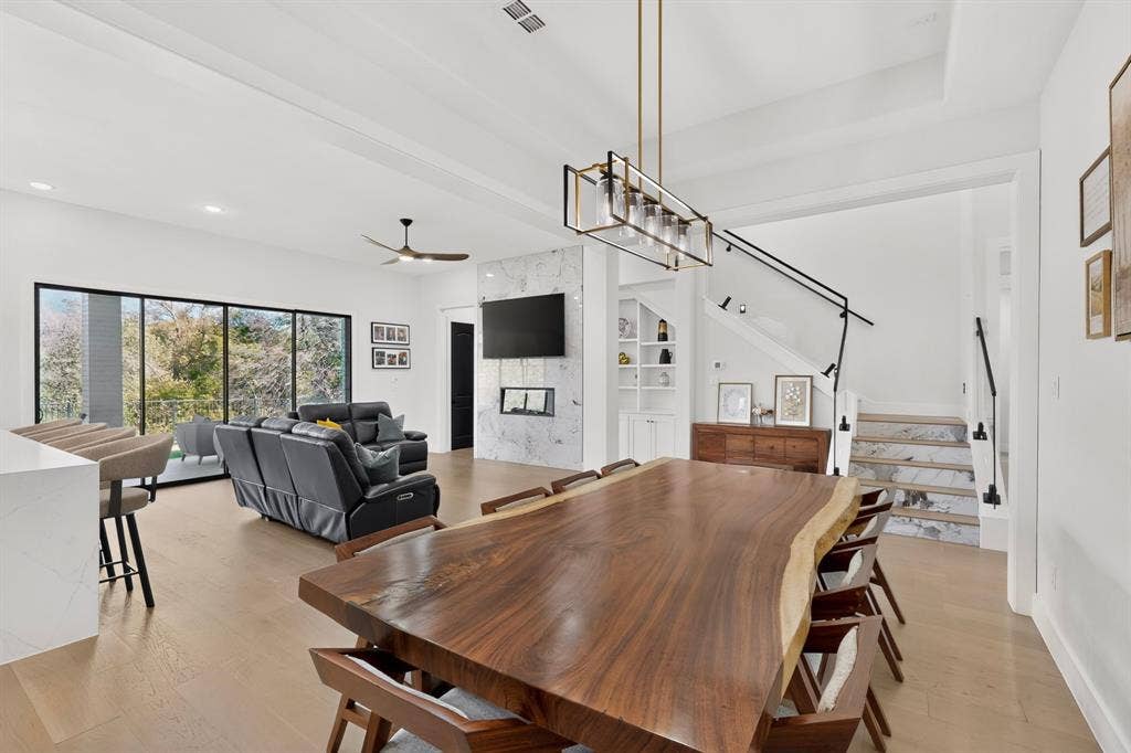 2519 Tamaron Cove, Cedar Hill, TX 75104 Open-concept living space featuring wood-finish flooring, a contemporary fireplace with a stone surround, and an elegant staircase with a black metal railing
