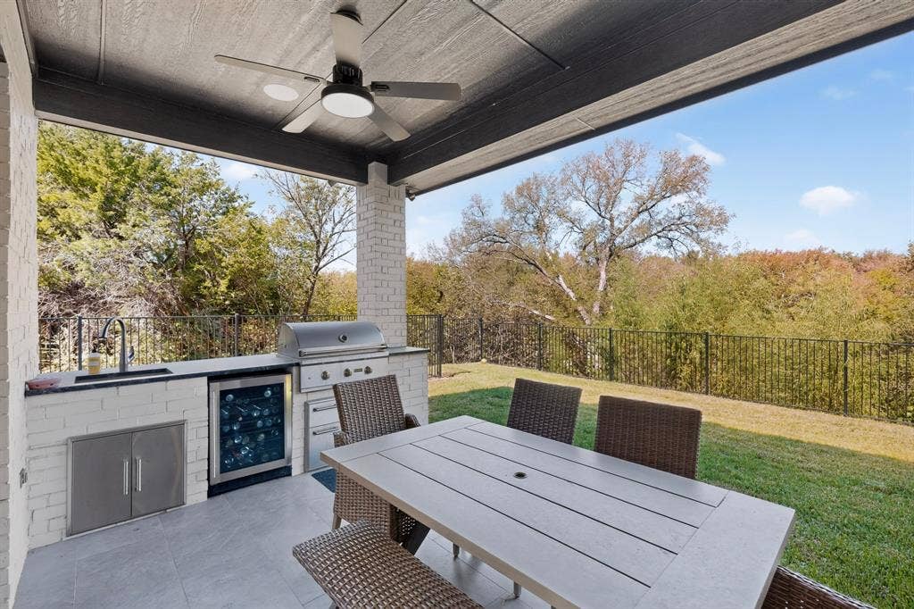 2519 Tamaron Cove, Cedar Hill, TX 75104 Covered patio with a built-in outdoor kitchen, stainless steel grill, refrigerator, and sink, set on a tiled surface