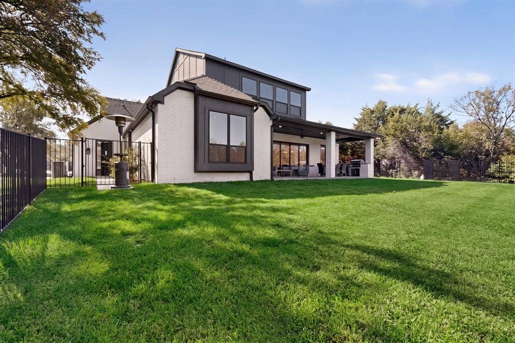 2519 Tamaron Cove, Cedar Hill, TX 75104 Expansive backyard featuring a manicured lawn, covered patio, and black metal fencing