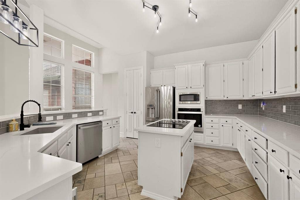 4237 McAlice Drive, Plano, TX 75093 White cabinetry, stainless steel appliances, central island with built-in cooktop, light-colored countertops, and tiled flooring