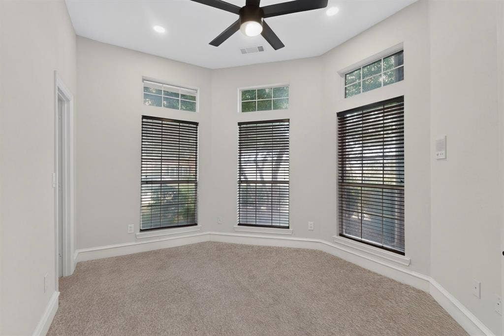4237 McAlice Drive, Plano, TX 75093 Light gray walls with white trim, gray carpet flooring, a black ceiling fan, and multiple windows with horizontal blinds