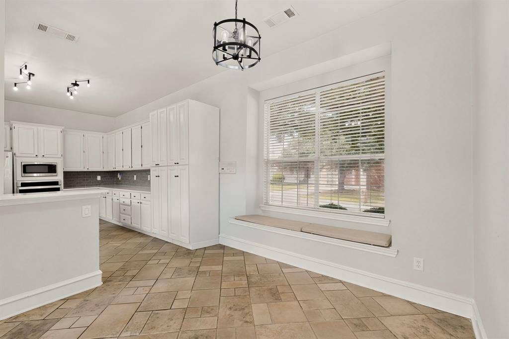 4237 McAlice Drive, Plano, TX 75093 White cabinetry with dark hardware, built-in microwave, tiled backsplash, and light-toned tile flooring