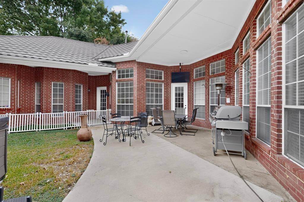 4237 McAlice Drive, Plano, TX 75093 Expansive concrete patio with a covered outdoor area, red brick exterior, and multiple large windows with grid patterns