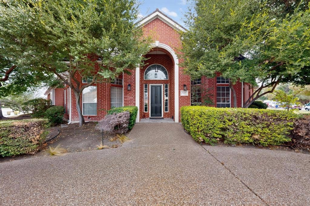 4237 McAlice Drive, Plano, TX 75093 Red brick exterior with an arched entryway, black front door, and transom window