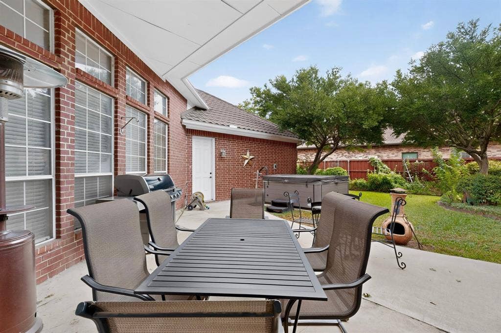 4237 McAlice Drive, Plano, TX 75093 Covered patio with brick exterior, large windows, and a built-in spa
