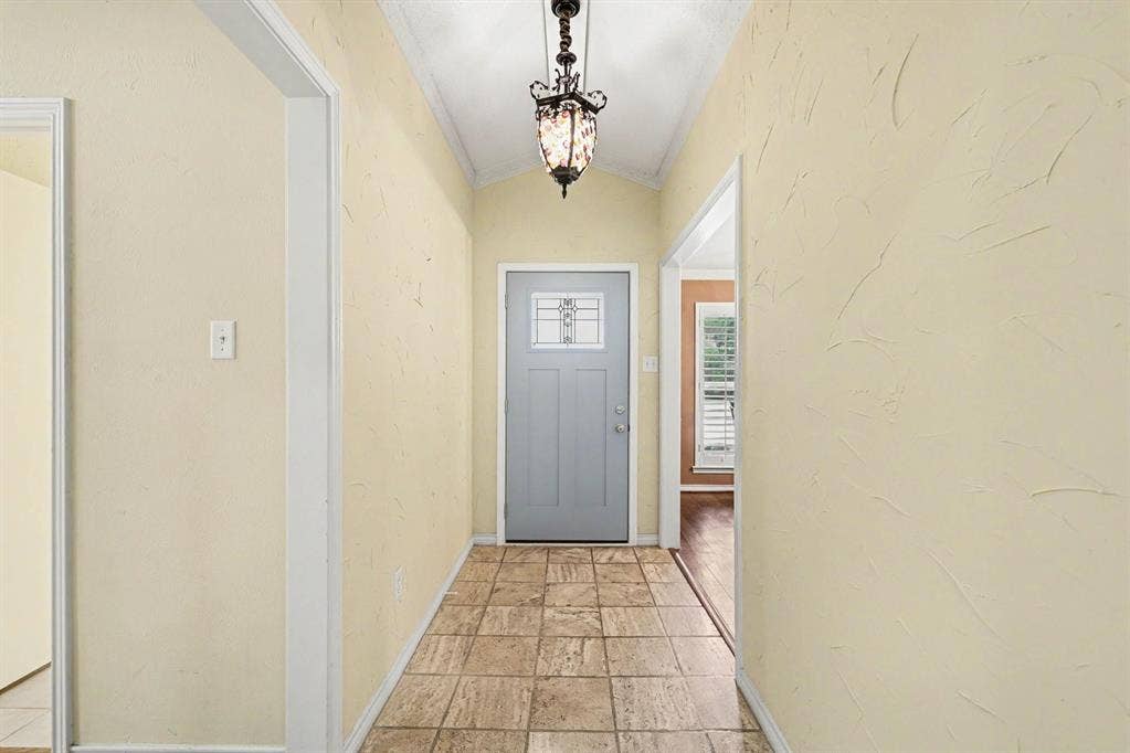 6503 Barfield Drive, Dallas, TX 75252 Vaulted ceiling with an ornamental chandelier, textured wall finish, and tile flooring