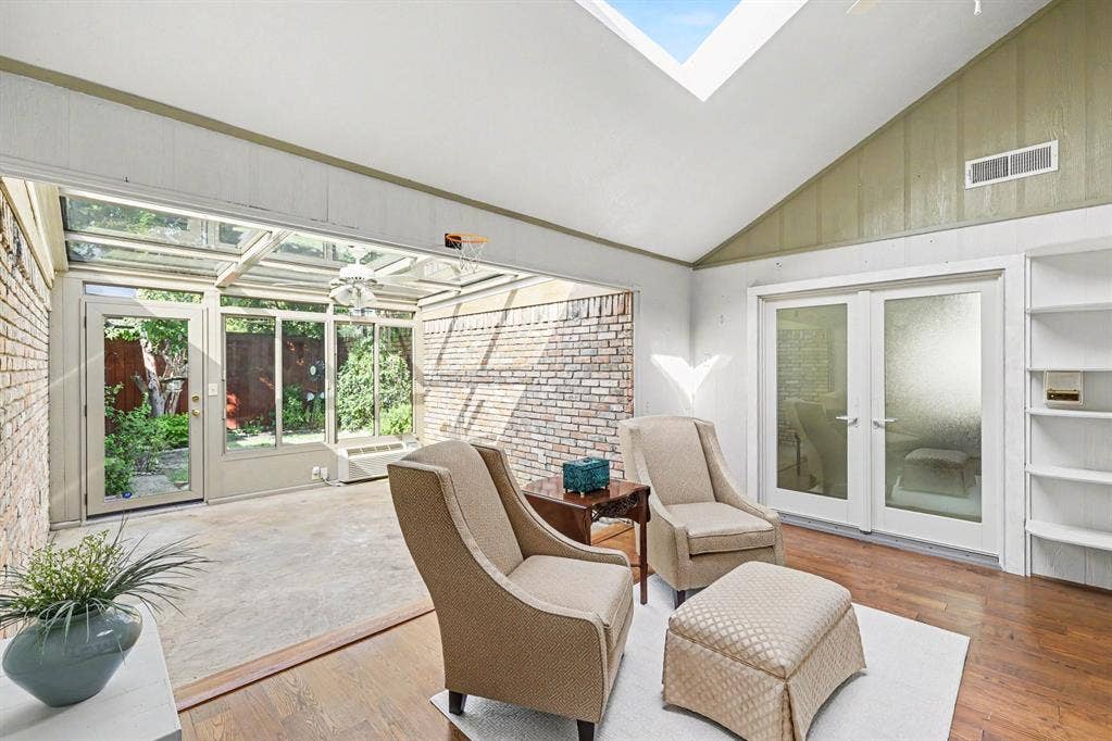 6503 Barfield Drive, Dallas, TX 75252 Vaulted ceiling with skylight, wood-finish flooring, built-in shelving, and frosted glass French doors