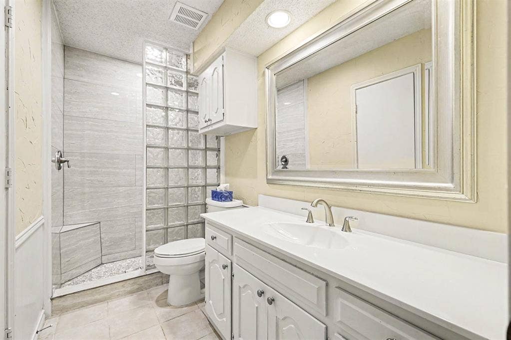 6503 Barfield Drive, Dallas, TX 75252 Walk-in shower with tiled walls and a built-in bench