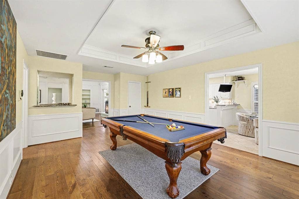 6503 Barfield Drive, Dallas, TX 75252 Wood-finish flooring throughout, tray ceiling with crown molding, ceiling fan with integrated lighting, and wainscoting on lower walls
