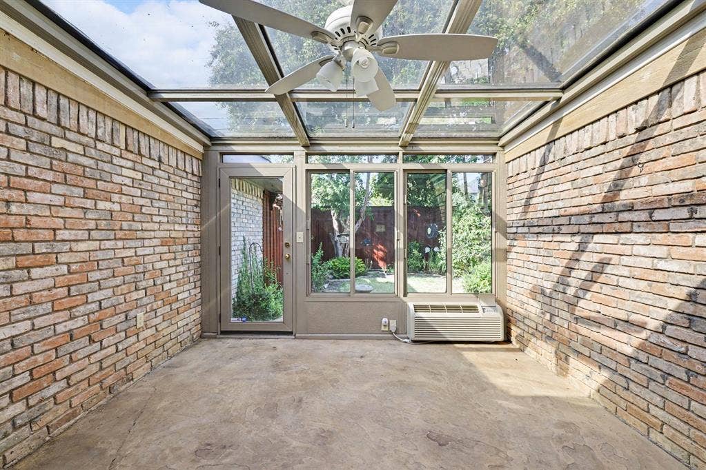 6503 Barfield Drive, Dallas, TX 75252 Sunroom with a glass roof, exposed brick walls, a ceiling fan, and concrete flooring