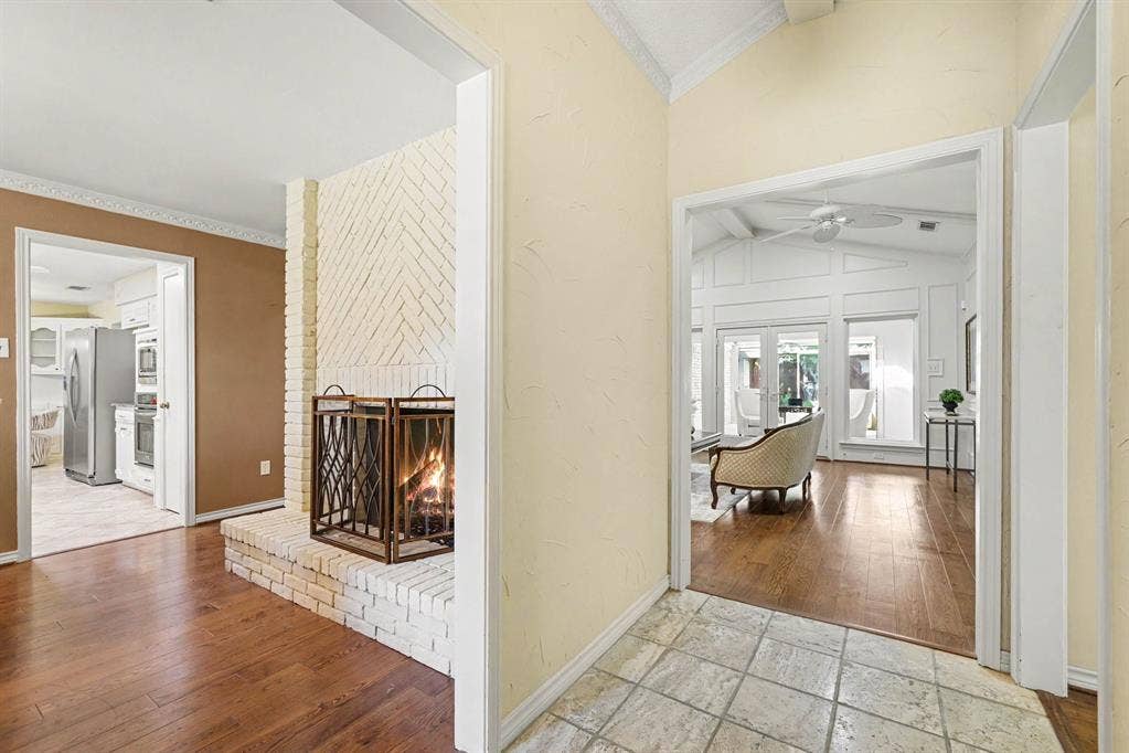 6503 Barfield Drive, Dallas, TX 75252 White brick fireplace with an elevated hearth, wood-finish flooring, and vaulted ceilings