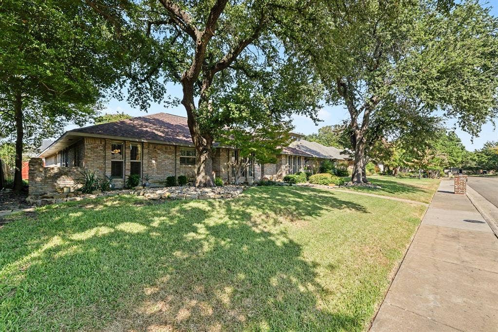 6503 Barfield Drive, Dallas, TX 75252 Brick exterior with a shingle roof, mature trees, and a concrete sidewalk