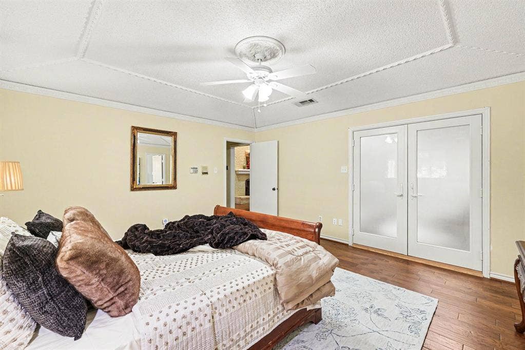 6503 Barfield Drive, Dallas, TX 75252 Wood-finish flooring, white double doors with frosted glass, ceiling fan with light fixture, decorative ceiling trim, and light yellow wall color