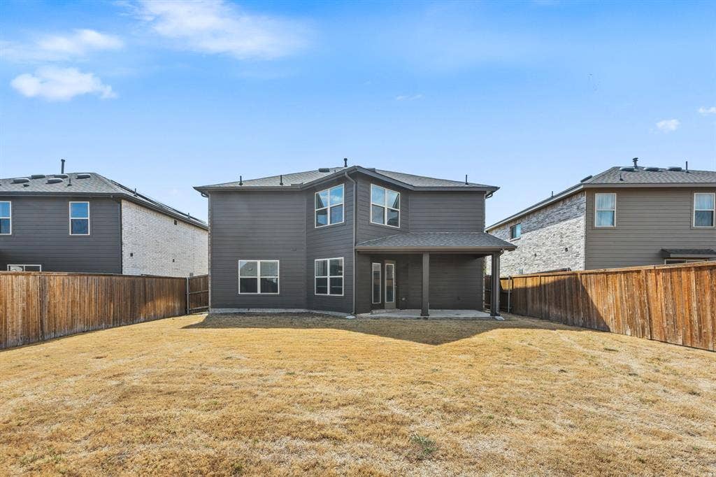 Expansive backyard with a wood privacy fence, covered patio,