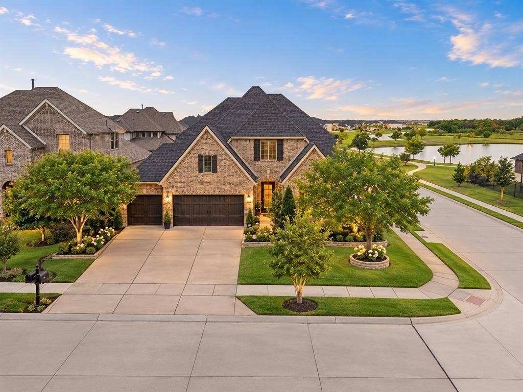 1734 Ellington Drive, Celina, TX 75009 Brick exterior with dark roofline and shutters, mature landscaping, expansive driveway, and a paved walkway