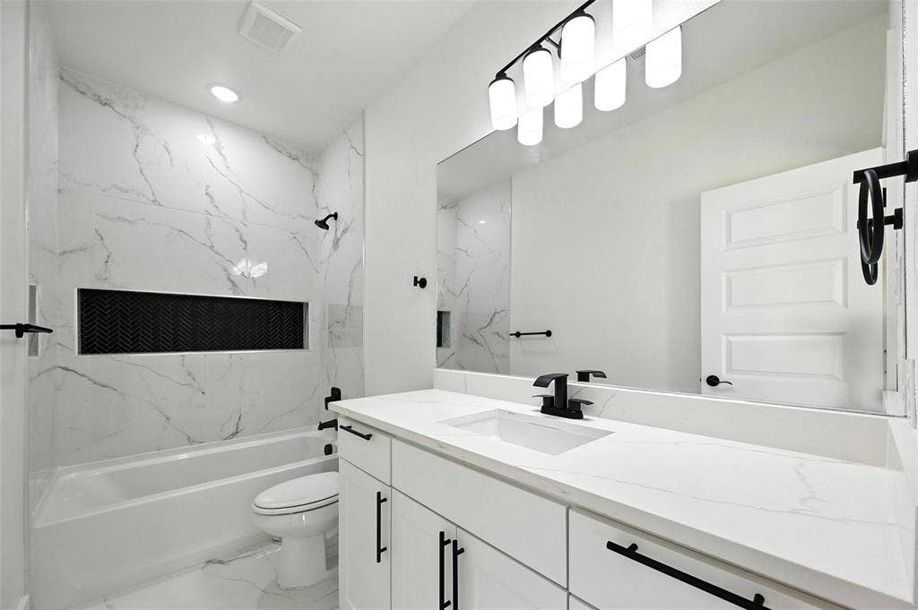 Integrated tub and shower with a recessed niche, featuring black herringbone tile