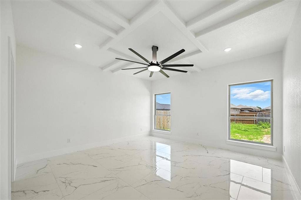 Tray ceiling with recessed lighting and a ceiling fan, two windows, and large-format tile flooring