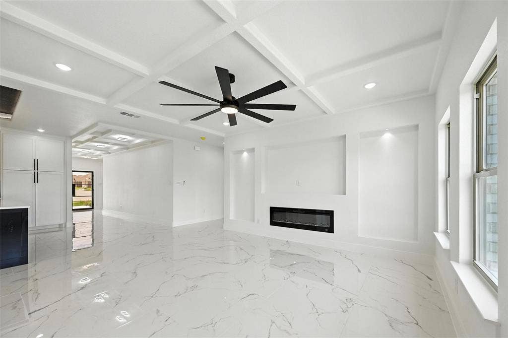 Coffered ceiling with recessed lighting and a ceiling fan, integrated fireplace, built-in wall niches, and polished tile flooring