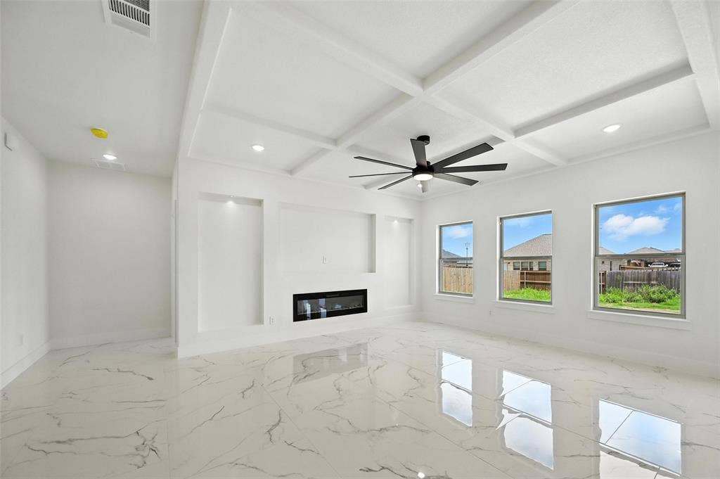 Coffered ceiling with a modern ceiling fan, recessed lighting, built-in fireplace, and large windows