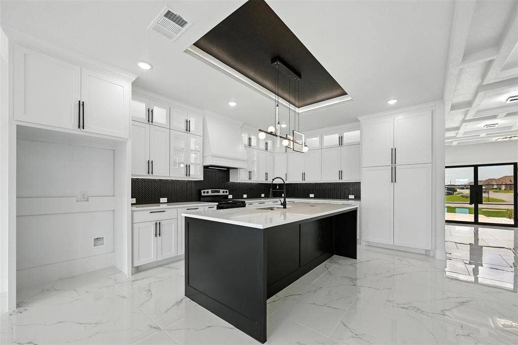 Modern kitchen featuring an expansive center island, white cabinetry, integrated range, and dark backsplash