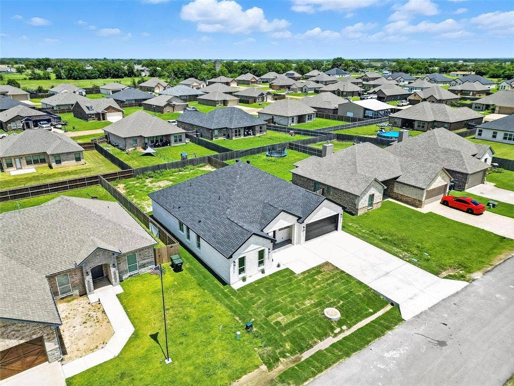 New construction residence featuring a black shingle roof, white exterior with black trim, an attached two-car garage, and a concrete driveway