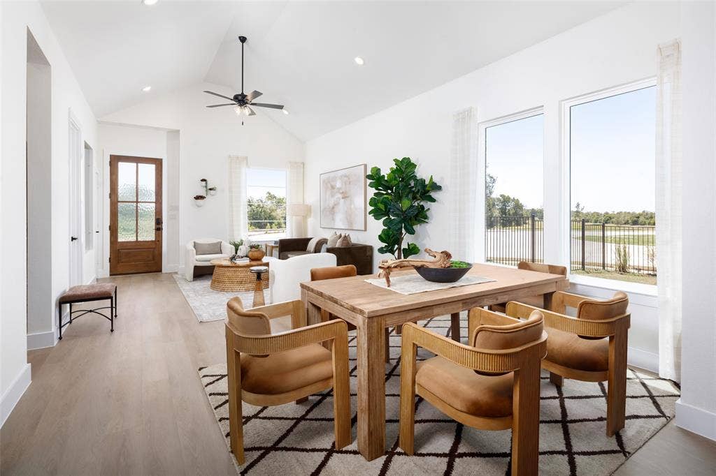 Open-concept interior featuring wood-finish flooring, vaulted ceiling, and multiple large windows