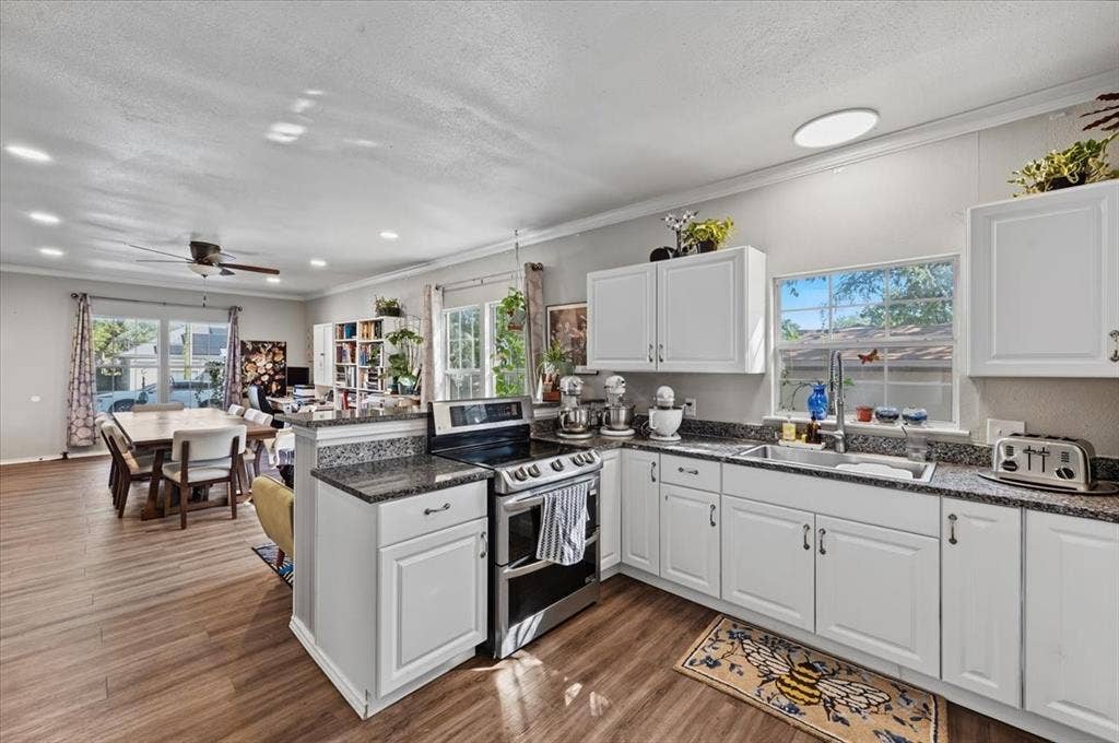 809 W Bridge Street, Weatherford, TX 76086 White cabinetry with dark countertops, stainless steel appliances, and wood-finish flooring