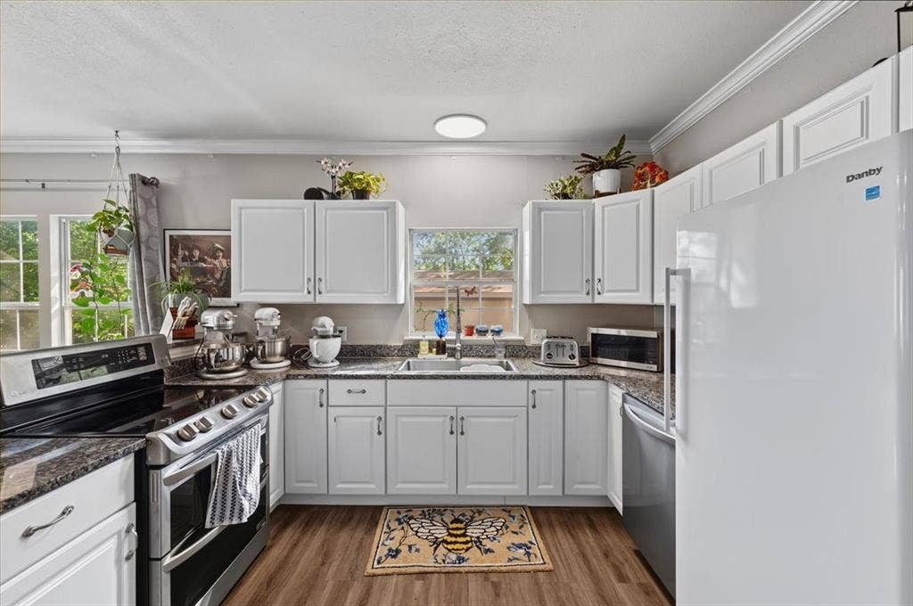 809 W Bridge Street, Weatherford, TX 76086 Kitchen featuring white cabinetry, wood-finish flooring, and dark speckled countertops