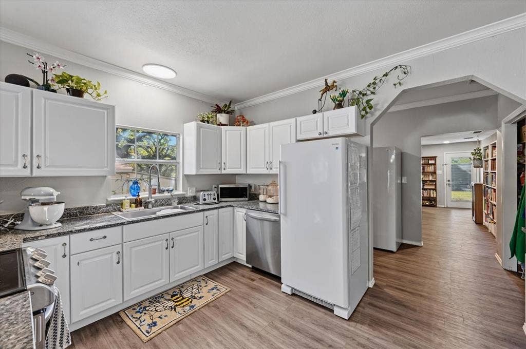 809 W Bridge Street, Weatherford, TX 76086 White shaker-style cabinetry, granite-finish countertops, stainless-steel appliances, wood-finish flooring, and crown molding